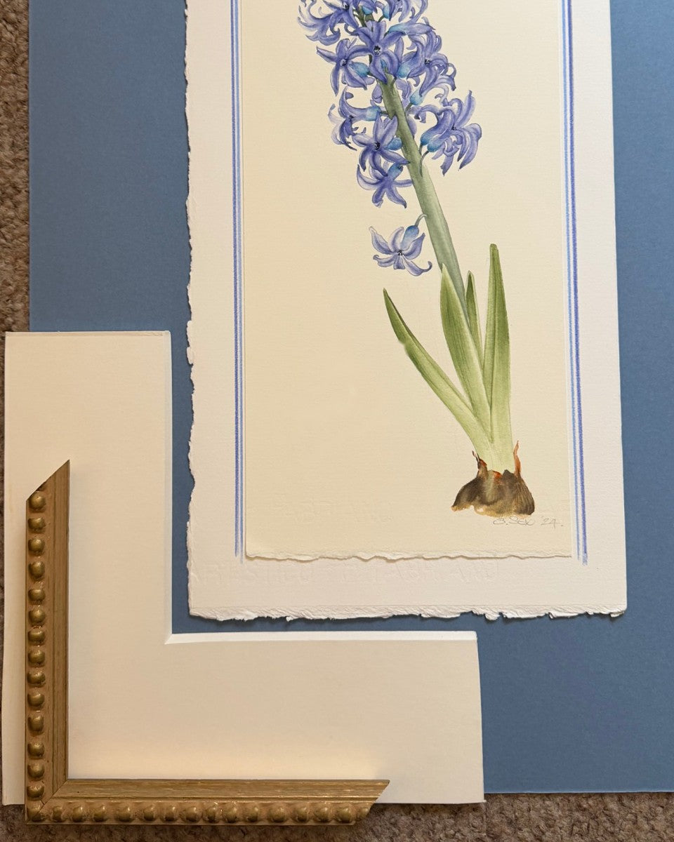 Hyacinth watercolour on deckle-edged paper with a cream mount sample and a beaded gold moulding corner laid over it.
