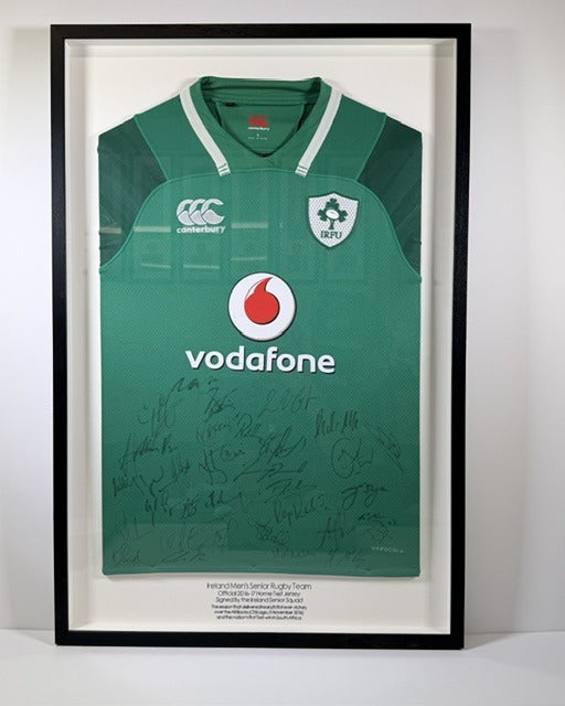 Signed green Ireland rugby jersey in a black frame with a white mount and a line of lettering underneath.